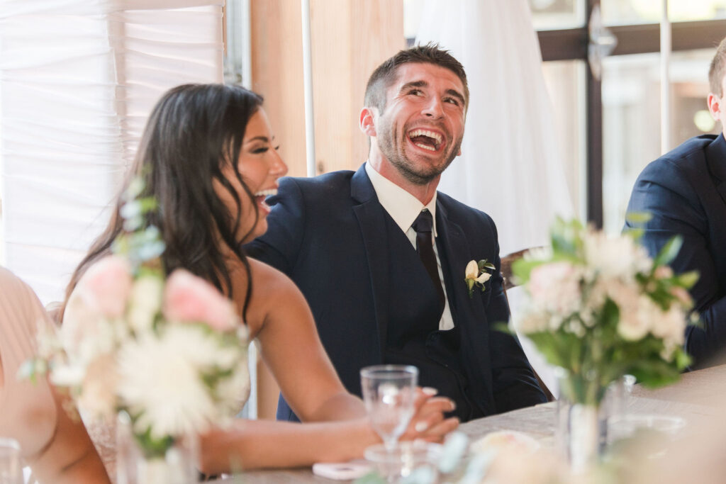 Bride and Groom laughing as they are hearing their wedding party speeches. 
