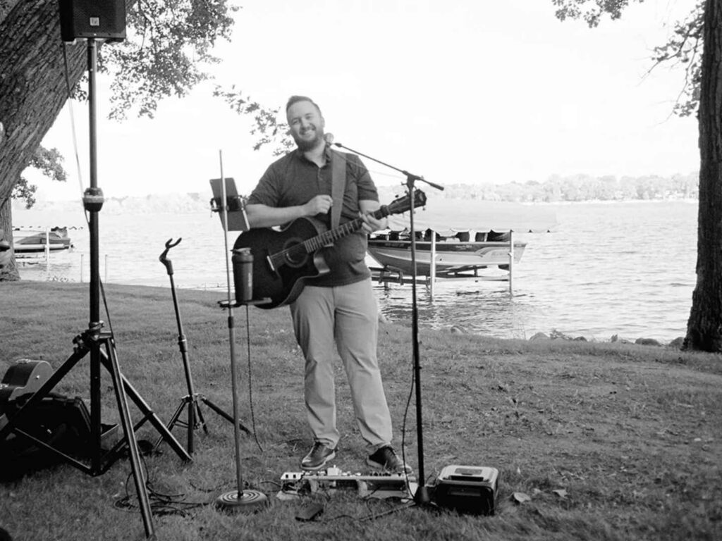 DJ Mike Nelson playing acoustic guitar during cocktail hour by the lake in Alexandria, MN
